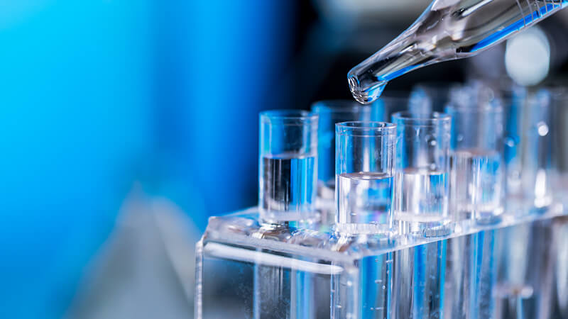 Pipettieren einer Flüssigkeit in Reagenzgläser die in Reagenzglashalter stehen