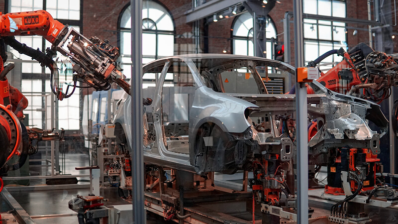 Roboterarme bauen ein Auto in deiner Industriehalle - IT-Sicherheit ist ein wichtiger Baustein