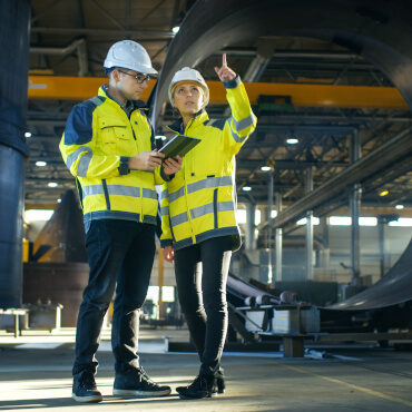 Personen mit Schutzausrüstung in Produktionshalle